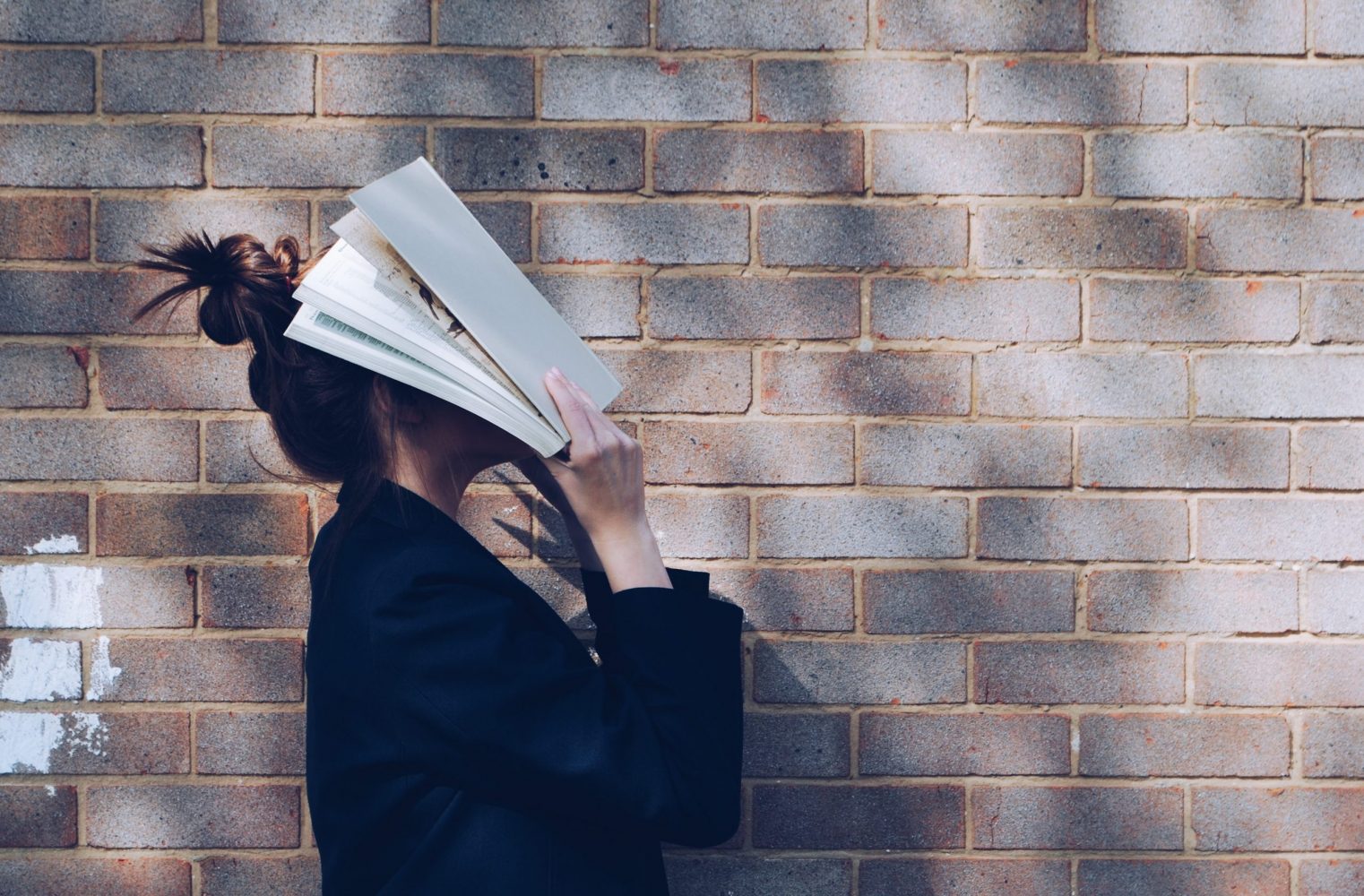 Woman with book over her face